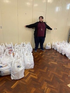 Oliver standing proudly surrounded by bags that he has packed for The Bread and Butter Thing.